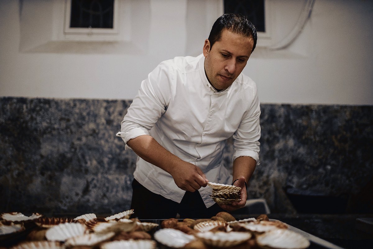 Chef de Abalone preparando conchas de vieira en el pase, antes del servicio de un evento