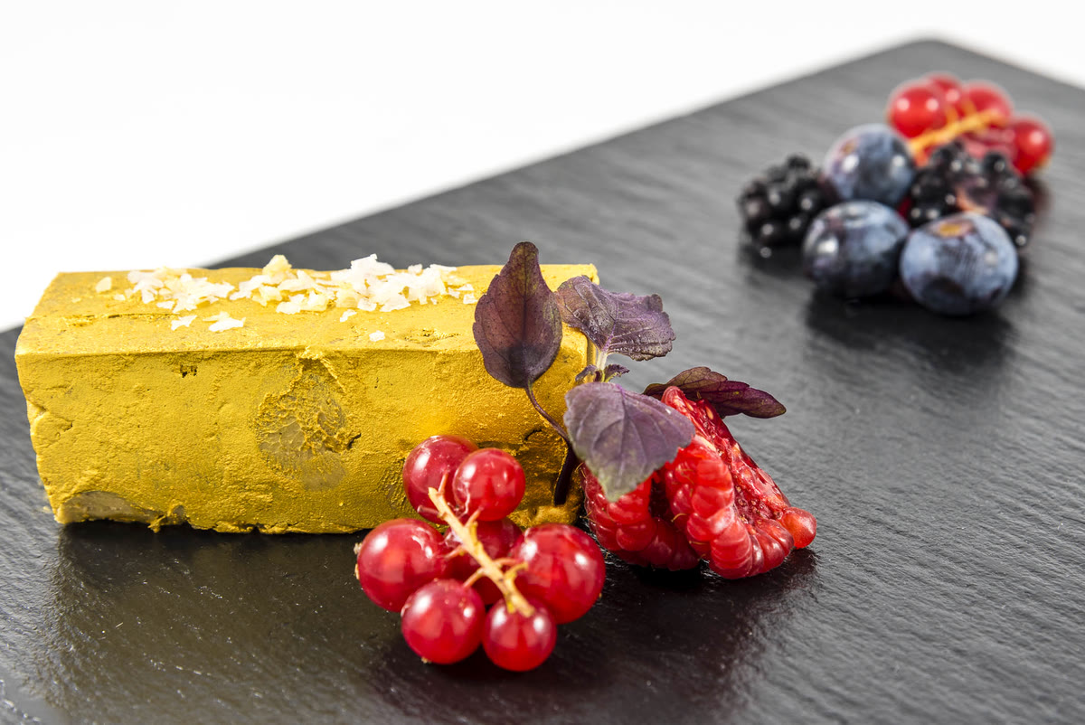 Bloc de foie con escamas de sal, grosellas y frutos rojos sobre pizarra negra