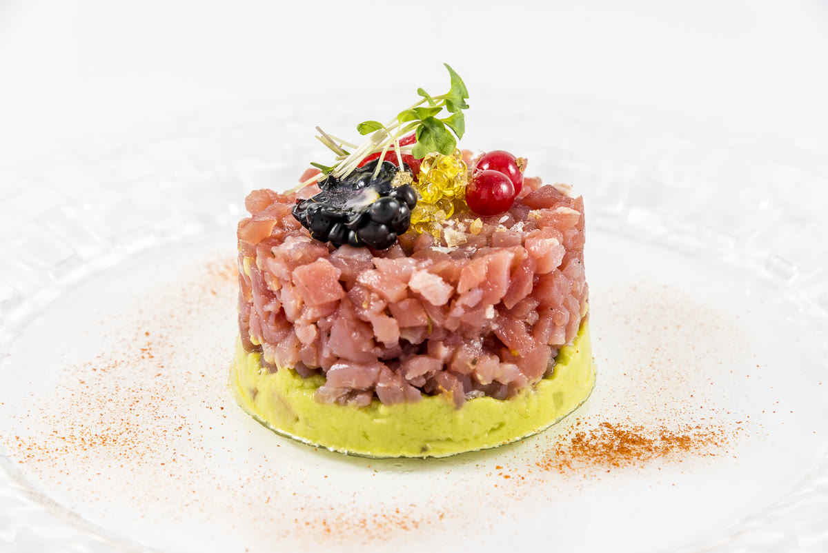 Tartar de atún sobre crema de aguacate coronado con grosellas y brotes frescos
